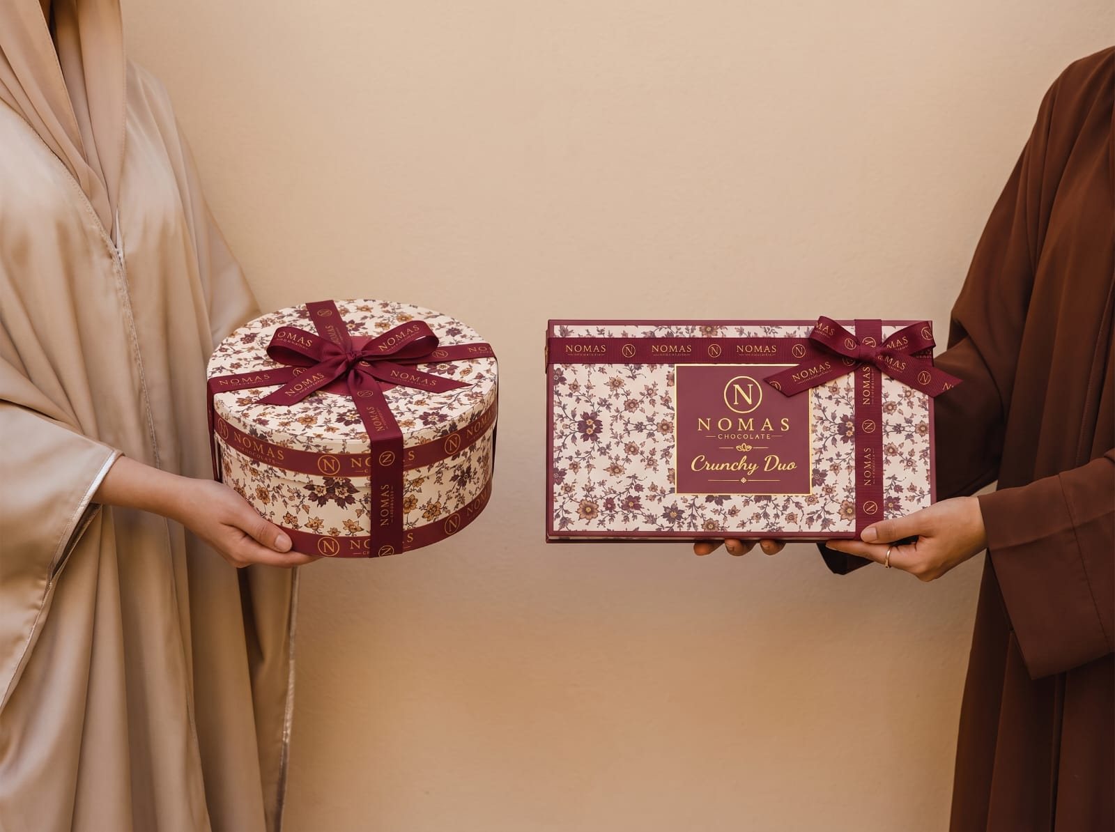Two Nomas boxes passed from hand to hand as a gift