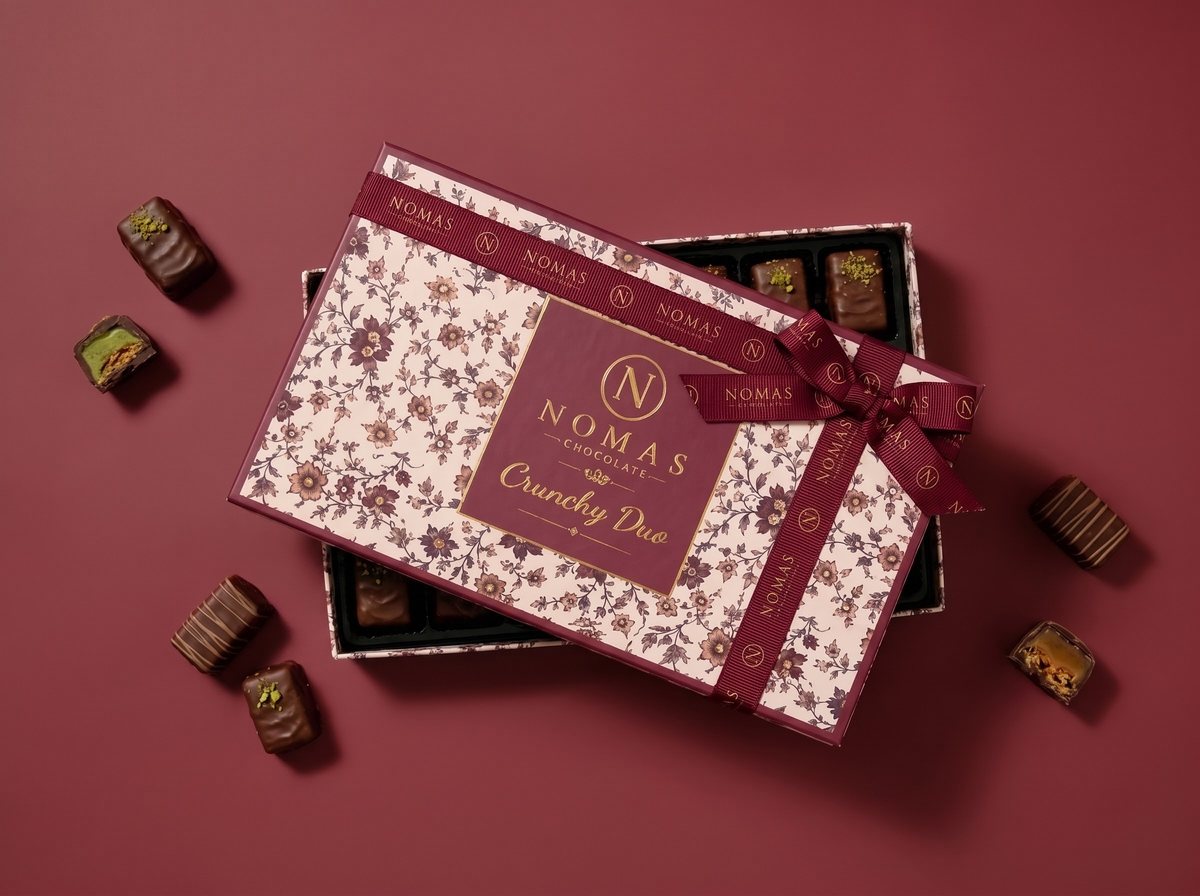The Crunchy Duo box with chocolate pieces on a burgundy background